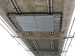 Single-tuned mass damper fitted to the underside of the concrete decking of the smaller arch of the bridge. Infinity Bridge tuned mass damper on small arch-1632.jpg