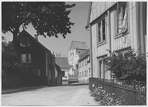 Fotografi av Kyrkogatan i Ronneby från 1942 med det Gaddska huset till vänster i bild på sin ursprungliga plats i kvarteret Victor. Fotografi av Mårten Sjöbeck ur Riksantikvarieämbetets samlingar.