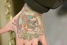 Sailor's hand with a tattoo of a skull, anchor, lifebuoy, and damage controlman insignia (axe and maul), in 2019 Person's hand with tattoo of skull, anchor, and life preserver.jpg