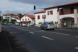 Route large avec quelques voitures et un feu vert.