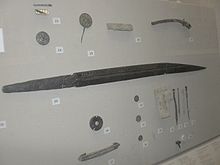 Museum display case with a long iron seax and other artefacts