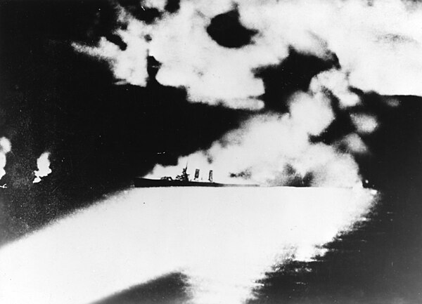 USS Quincy being illuminated by searchlights of Chōkai, on fire and sinking from Japanese torpedoes