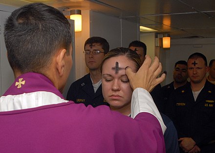 A priest marks a cross of ashes on a worshipper's forehead, the prevailing form in English-speaking countries.[64]