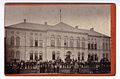 Deutsch: Zu den Berliner Fotografenateliers im 19. Jahrhundert gehörte eines von dem Hoffotografen Edmund Risse, der ausweislich dieser Carte de Visite mit der Abbildung des Gebäudes einer Berliner Schule mit zahlreichen Schülern und Lehrern davor sein Atelier in der Straße Unter den Linden 15 betrieb. Laut der von der Professorin Sibylle Einholz betreuten Webseite Berliner Fotografenateliers des 19. Jahrhunderts betrieb Edmund Risse sein erstes Atelier in Berlin unter der genannten Adresse lediglich von 1880 bis 1883, so dass von einer Entstehung dieser Aufnahme in eben jenem Zeitraum ausgegangen werden muss. Diese Datumsangaben präzisieren zugleich die Eingrenzung der auf dem Revers genannten weiteren Ateliers, die zeitgleich in anderen Städten betrieben wurden ...