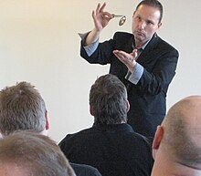 Guy Bavli holds up a bent spoon in front of a small audience