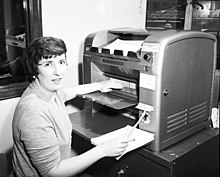 A worker loads documents into an Ozalid printer. City Light office worker, 1954.jpg