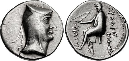 Two sides of a silver coin. The one on the left bears the imprint of a man's head, while the one on the right a sitting individual.