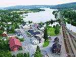 Luftbild einer Ortschaft mit einem Bahnhof an einem See