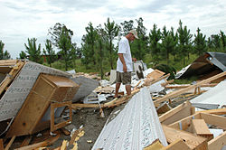 A homeowner looks through what is left of his home after Hurricane Dennis caused severe damage, 2005