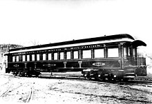 black and white photograph of a railroad passenger car with 15 passenger windows on each side, and decorative gilding on the paneling between each window. Along the top is printed, "KANSAS CITY, FORT SMITH & SOUTHERN."