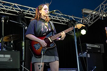 Soccer Mommy playing guitar and singing onstage