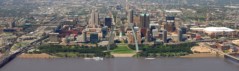 Panorama panorama města s velkým šedým obloukem uprostřed, šedomodrou řekou v popředí a četnými mrakodrapy v pozadí