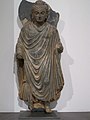 Bouddha debout, vêtu comme un ascète, et comme les moines[N 17]. Gandhara, Ier – IIIe siècle schiste, Musée Guimet
