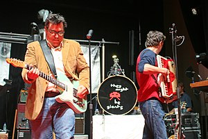 Photograph of a group singing and playing instruments on stage.