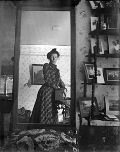 Mujer tomándose una fotografía frente a un espejo en torno a 1900.