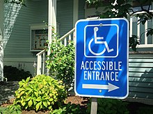 A sign indicating the location of the wheelchair ramp and entrance. Wheelchair ramp sign .jpg