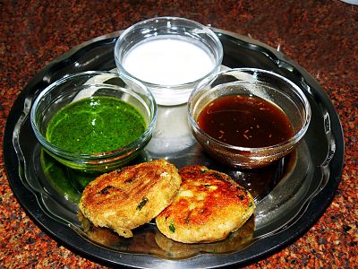 Aloo tikki served with mint and tamarind sauce and dahi (yogurt) in India.