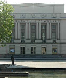 The statue with the Pomeranian Philharmonic building in the backdrop