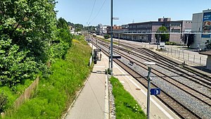 Sidewalk leading down to platform next to triple-tracked railway line