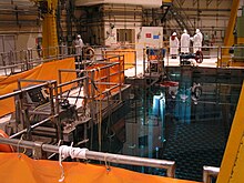 A group of people in radiation suits looking at a fuel pool