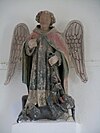 Saint Michael heykelinin duvara sabitlenmiş beyaz bir kaide üzerinde renkli fotoğrafı.
