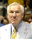 Muž v šedé bundě a žluté kravatě s modrými puntíky