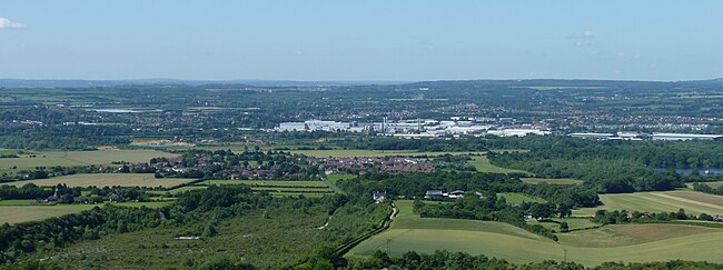 A panoramic photograph of the view across a wide river valley with areas of countryside mixed with buildings