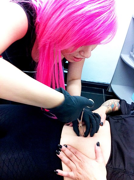 Piercer using a clamp in the early stages of the navel piercing process