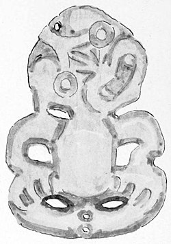 A greenstone carving of a tiki with a small hole at the top of the head to allow for a cord to be passed through.
