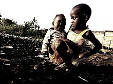 Little girl taking care of her young sister in a slum. Power of a female.jpg