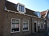 Pand onder zadeldak, evenwijdig aan de straat. In de 19e eeuw samengetrokken uit twee woningen. Dakkapellen met vleugelstukken.