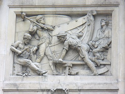 A relatively modern high relief (depicting shipbuilding) in Bishopsgate, London. Note that some elements jut out of the frame of the image.