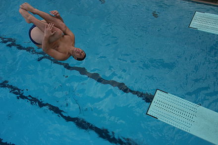 A male diver performs a reverse in the tuck position from a 3-meter springboard
