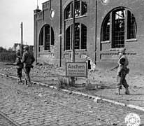 SC 195646 - Yank infantrymen pass a city limits sign of Aachen, Germany, still very much on the alert as Nazi snipers may be hidden in the building. 13 October, 1944. (52608591996).jpg