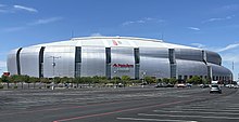 The large, gray State Farm Stadium behind an empty parking lot