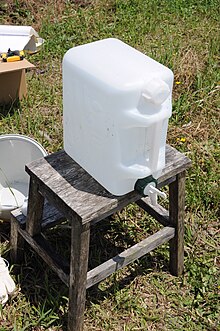 A water canister with a screw cap on top and tap on bottom. Stock water (4677305871).jpg