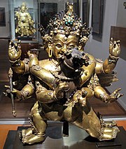Kuva kultaisesta patsasta museossa pienestä hahmosta, jossa on useita käsiä ja jalkoja.