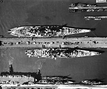 An Iowa-class battleship (Missouri), 887 ft (270 m) and 57,540 long tons (58,460 t), the largest U.S. Navy battleship class (top), and Alaska, 808 ft (246 m) and 29,771 long tons (30,249 t), moored at the same pier USS Missouri (BB-63) and USS Alaska (CB-1) at Norfolk, Virginia, 1944.jpg