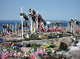 Le cimetière d'Upernavik, au Groenland. Le sol ne pouvant être creusé, les cercueils sont déposés en surface puis recouverts de pierres ou de ciment. Les tombes sont décorées avec des fleurs artificielles. (définition réelle 2 200 × 1 622)