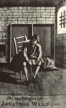 Jonathan Wild sits in Newgate Prison, with his account book on his knees. Wild continued, while in prison, to keep his "list" of goods that came into his office and the money paid for them. Wild-sm.gif