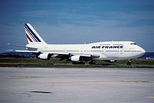 Vue de trois quart face d'un quadriréacteur 747-300. Une « bosse » au-dessus de la partie du fuselage indique le pont supérieur.