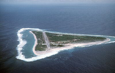 Une piste d'atterrissage et un mât d'antenne rouge et blanc sur une petite, vert, île triangulaire
