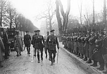 Fotografía en blanco y negro de oficiales británicos pasando junto a soldados franceses.