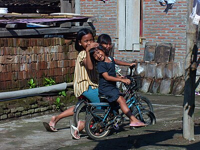 Tiga anak perempuan Bantul sedang berpose sambil menaiki sepeda.