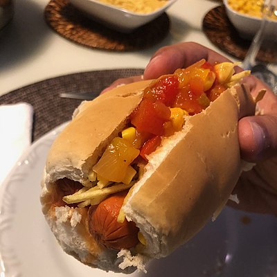 Brazilian hot-dog with tomato, corn, batata-palha (straw-fries) and onion