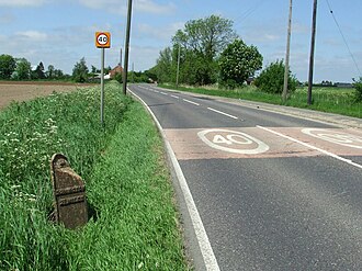 A152 at Monks Hall, showing speed limit and 19th century milepost Cast Iron Milepost, A152.jpg