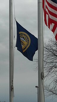 The flags of Nebraska and the United States at half-mast – note that the state flag is still lower than the national flag