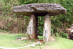 A tall dolmen consisting of two standing stones carrying one horizontal stone on top.