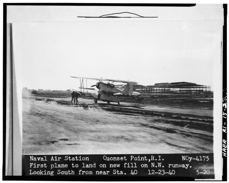 File:LOOKING SOUTH AT FIRST PLANE TO LAND ON FILL (RUNWAY 16-34) LANDPLANE HANGARS (BLDGS. 3-4) VISIBLE IN BACKGROUND. USN PHOTO, DECEMBER 23, 1940. - Quonset Point Naval Air Station, HAER RI,5-KINGN,6-22.tif