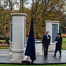 two people standing in from a memorial that is three pillars on a circular black stone base.